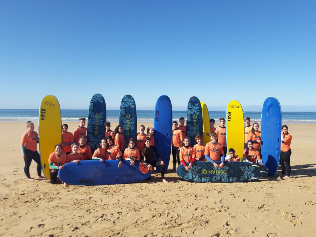 Schüler*innen stehen vor Surfbrettern am Strand